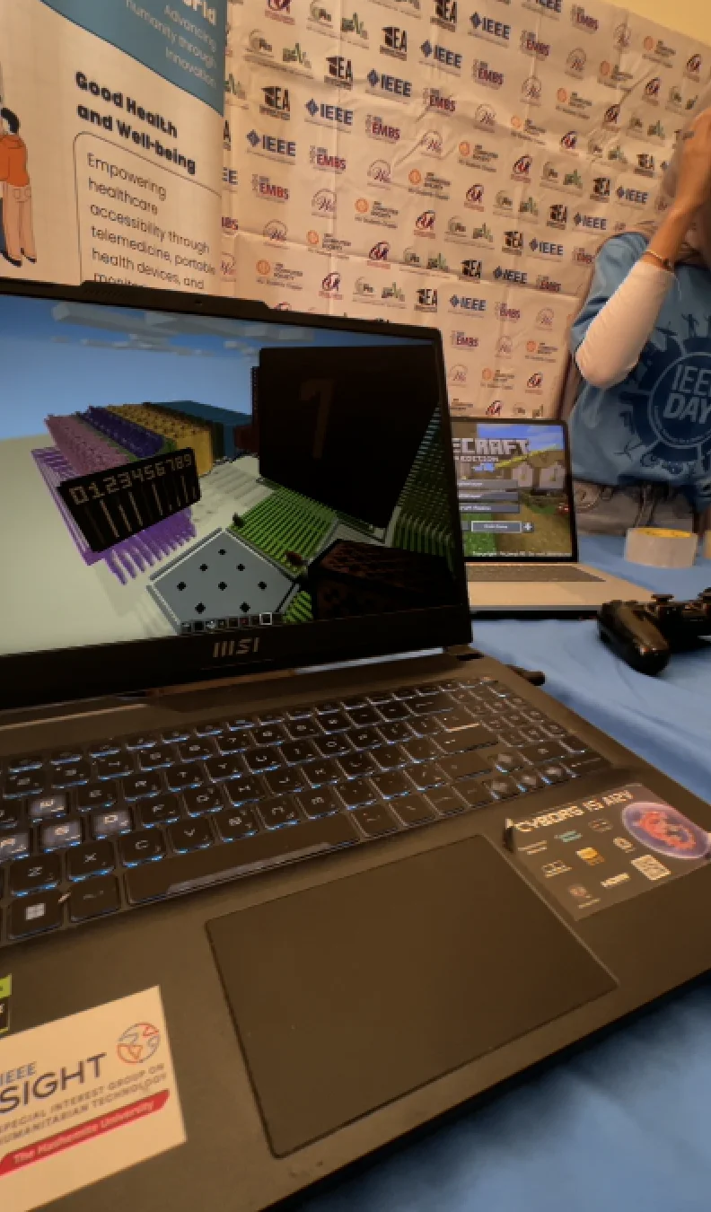 A laptop displays a humanitarian technology project at the IEEE Day 2025 exhibition.